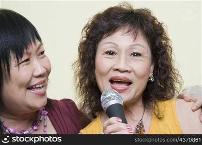Portrait of a senior woman singing with a mature woman in front of a microphone