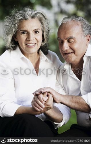 Portrait of a senior woman smiling with a senior man holding her hands