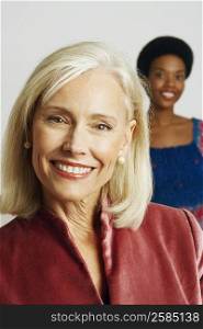 Portrait of a senior woman smiling with a young woman in the background