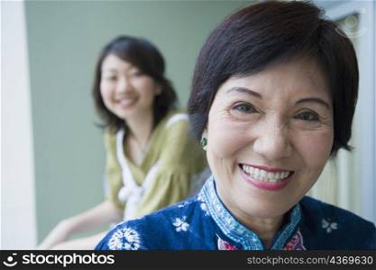 Portrait of a senior woman smiling with her granddaughter standing behind her
