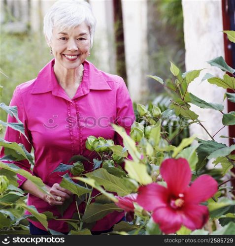 Portrait of a senior woman standing behind plants