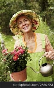 Portrait of a senior woman watering in a potted plant and smiling