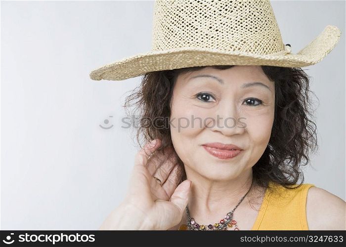 Portrait of a senior woman wearing a straw hat and posing