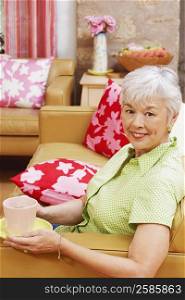 Portrait of a senior woman with a cup of coffee sitting on a couch