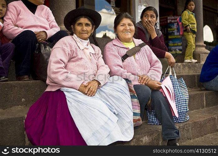 Portrait of a senior woman with a mid adult woman sitting on steps, Peru