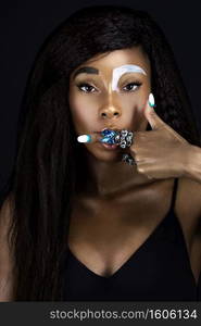 Portrait of a sensual young black female with blowdried long wavy hair, beautiful makeup, moist lips and white nails posing by herself in a studio with a dark background showing 1 finger with jewelry.