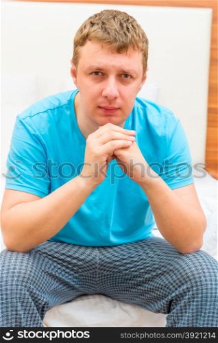 portrait of a serious man of 30 years sitting on a bed