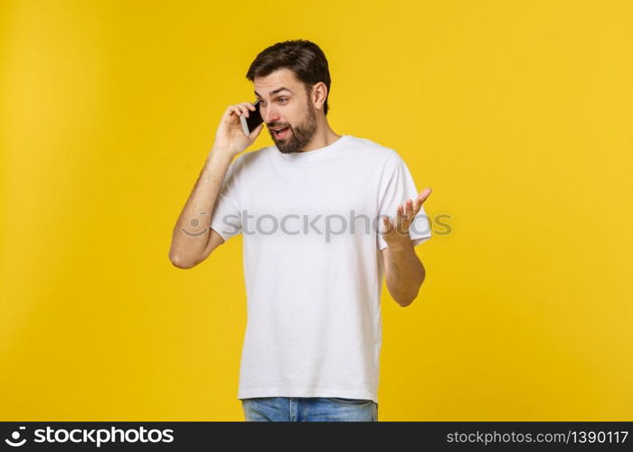 Portrait of a serious man talking on the phone isolated on a yellow background. Looking at camera.. Portrait of a serious man talking on the phone isolated on a yellow background. Looking at camera