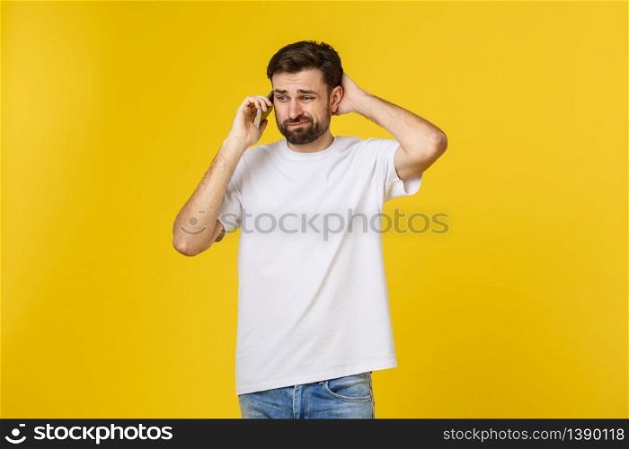 Portrait of a serious man talking on the phone isolated on a yellow background. Looking at camera.. Portrait of a serious man talking on the phone isolated on a yellow background. Looking at camera