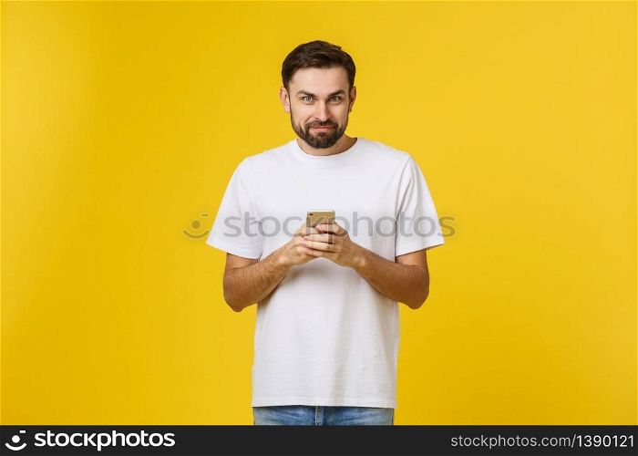Portrait of a serious man talking on the phone isolated on a yellow background. Looking at camera.. Portrait of a serious man talking on the phone isolated on a yellow background. Looking at camera