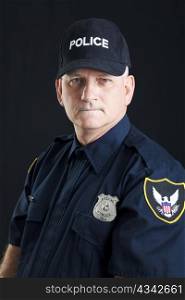 Portrait of a serious police officer, photographed over a black background.