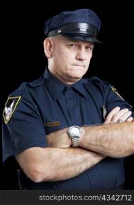 Portrait of a serious police officer with arms folded, against a black background.