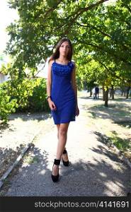 Portrait of a sexy young female in a park in blue dress