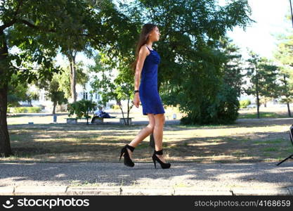 Portrait of a sexy young female in a park in blue dress