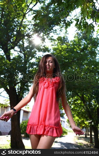 Portrait of a sexy young female in a park in red dress