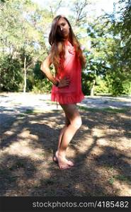 Portrait of a sexy young female in a park in red dress