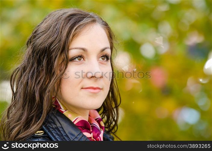 Portrait of a single-minded young girl in autumn clothes. Close-up portrait of a beautiful young girl on the background of Europeans autumn foliage