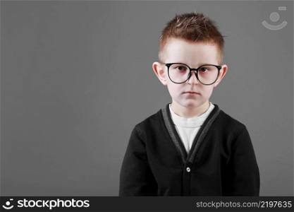 Portrait of a smart and sad child boy in glasses on a grey background close-up. Concept of school education, science and innovation, business development. copy space.. Portrait of a smart and sad child boy in glasses on a grey background close-up. Concept of school education, science and innovation, business development. copy space