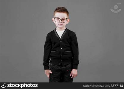 Portrait of a smart and serious child boy in glasses on a grey background close-up. Concept of school education, science and innovation, business development. copy space.. Portrait of a smart and serious child boy in glasses on a grey background close-up. Concept of school education, science and innovation, business development. copy space