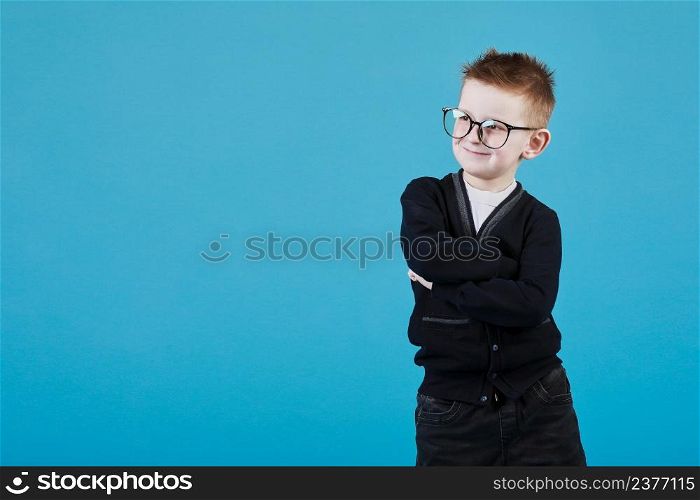 Portrait of a smart teenage boy in a blue shirt and glasses on a blue background close-up, folded his arms over his chest. Concept of school education, science and innovation, business development. Portrait of a smart teenage boy in a blue shirt and glasses on a blue background close-up, folded his arms over his chest. Concept of school education, science and innovation, business development.