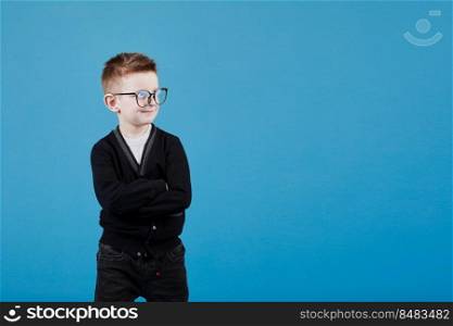 Portrait of a smart teenage boy in a blue shirt and glasses on a blue background close-up, folded his arms over his chest. Concept of school education, science and innovation, business development. Portrait of a smart teenage boy in a blue shirt and glasses on a blue background close-up, folded his arms over his chest. Concept of school education, science and innovation, business development.