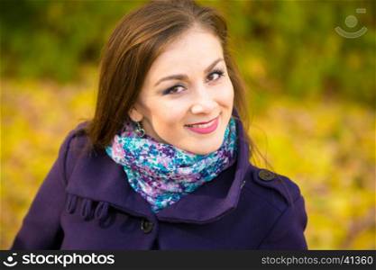Portrait of a smiling beautiful girl on the blurry background of autumn leaves