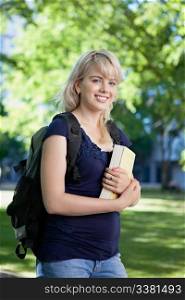 Portrait of a smiling college girl with book and bag