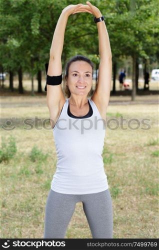 portrait of a smiling fitness woman stretching arms outdoor
