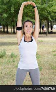 portrait of a smiling fitness woman stretching arms outdoor