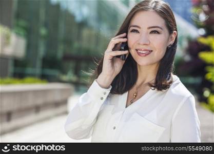 Portrait of a smiling happy young Asian woman or businessowman talking on her cell phone