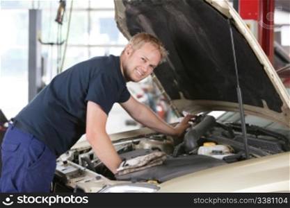 Portrait of a smiling mechanic working on a car in garage