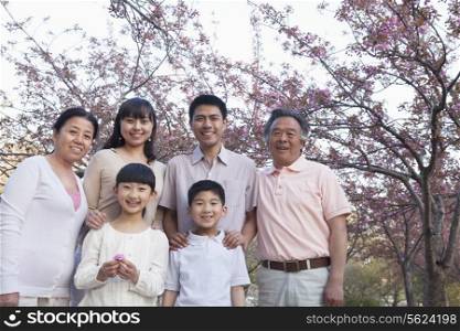 Portrait of a smiling multi-generational family amongst the cherry trees and enjoying the park in the springtime