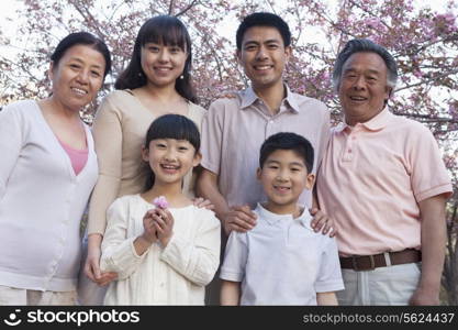 Portrait of a smiling multi-generational family amongst the cherry trees and enjoying the park in the springtime