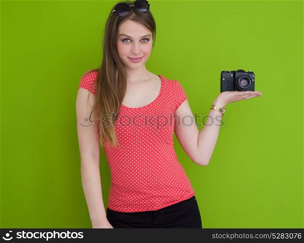 portrait of a smiling pretty girl taking photo on a retro camera isolated over green background