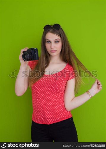 portrait of a smiling pretty girl taking photo on a retro camera isolated over green background