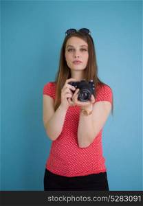 portrait of a smiling pretty girl taking photo on a retro camera isolated over blue background