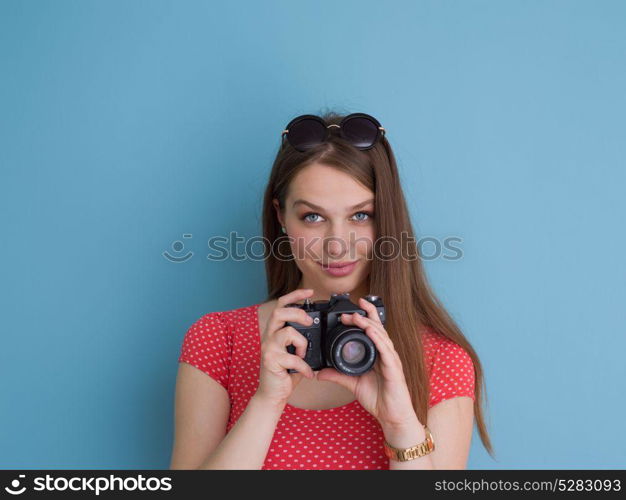 portrait of a smiling pretty girl taking photo on a retro camera isolated over blue background