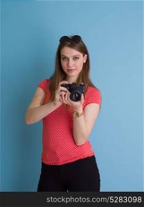 portrait of a smiling pretty girl taking photo on a retro camera isolated over blue background