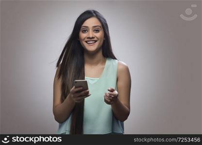 Portrait of a smiling teenage girl holding her mobile phone