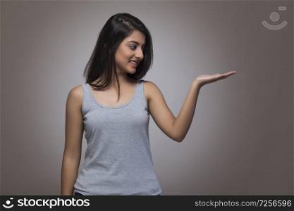 Portrait of a smiling teenage girl posing to show something in her palm and looking at it