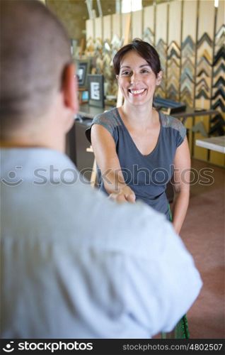 portrait of a smiling woman giving an handshake to customer