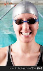 portrait of a smiling woman swimmer looking at camera with blurred swimming pool behind her