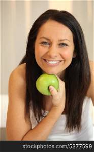 Portrait of a smiling woman with a Granny Smith apple