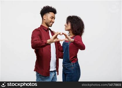 Portrait of a smiling young african couple dressed in casual clothes hugging and showing heart gesture with fingers isolated over white background.. Portrait of a smiling young african couple dressed in casual clothes hugging and showing heart gesture with fingers isolated over white background