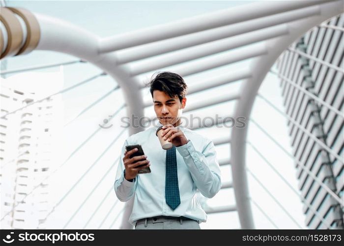 Portrait of a Smiling Young Asain Businessman Using Mobile Phone in the City