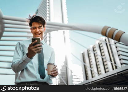 Portrait of a Smiling Young Asian Businessman Using Mobile Phone in the City