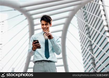 Portrait of a Smiling Young Asian Businessman Using Mobile Phone in the City