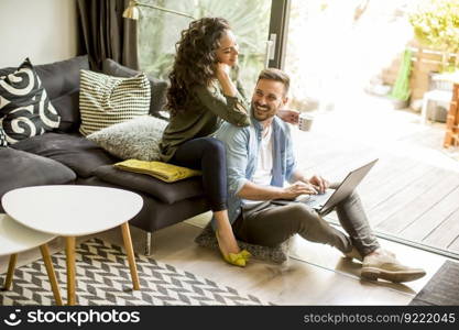 Portrait of a smiling young couple using laptop at home indoor