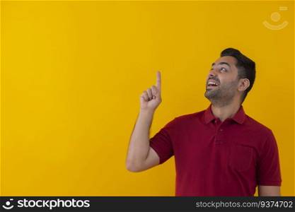 Portrait of a smiling young man pointing above against yellow background