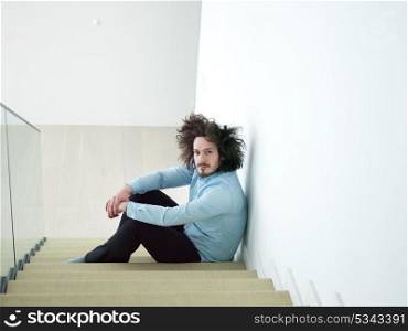 portrait of a smiling young man sitting on the stairs at home